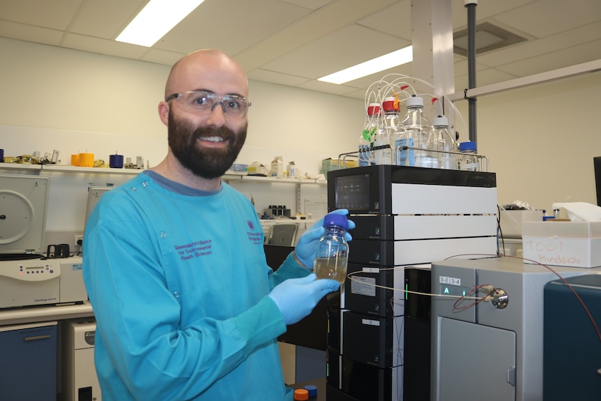 Photo of Dr Rory Verhagen holding a test tube with scrubbed drainage